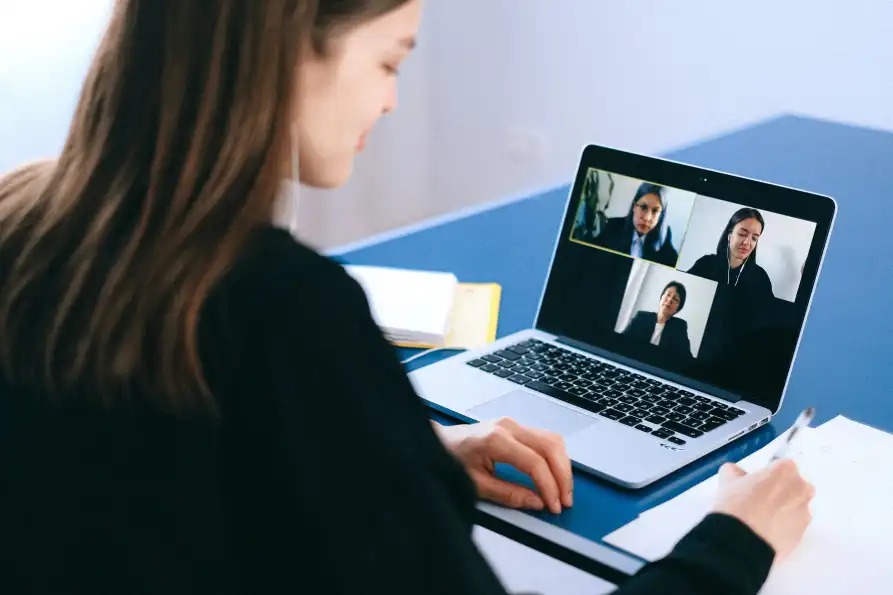 Op haar laptop spreekt een vrouw met drie collega’s in een online meeting. Zo blijft ze verbonden tijdens het thuiswerken.